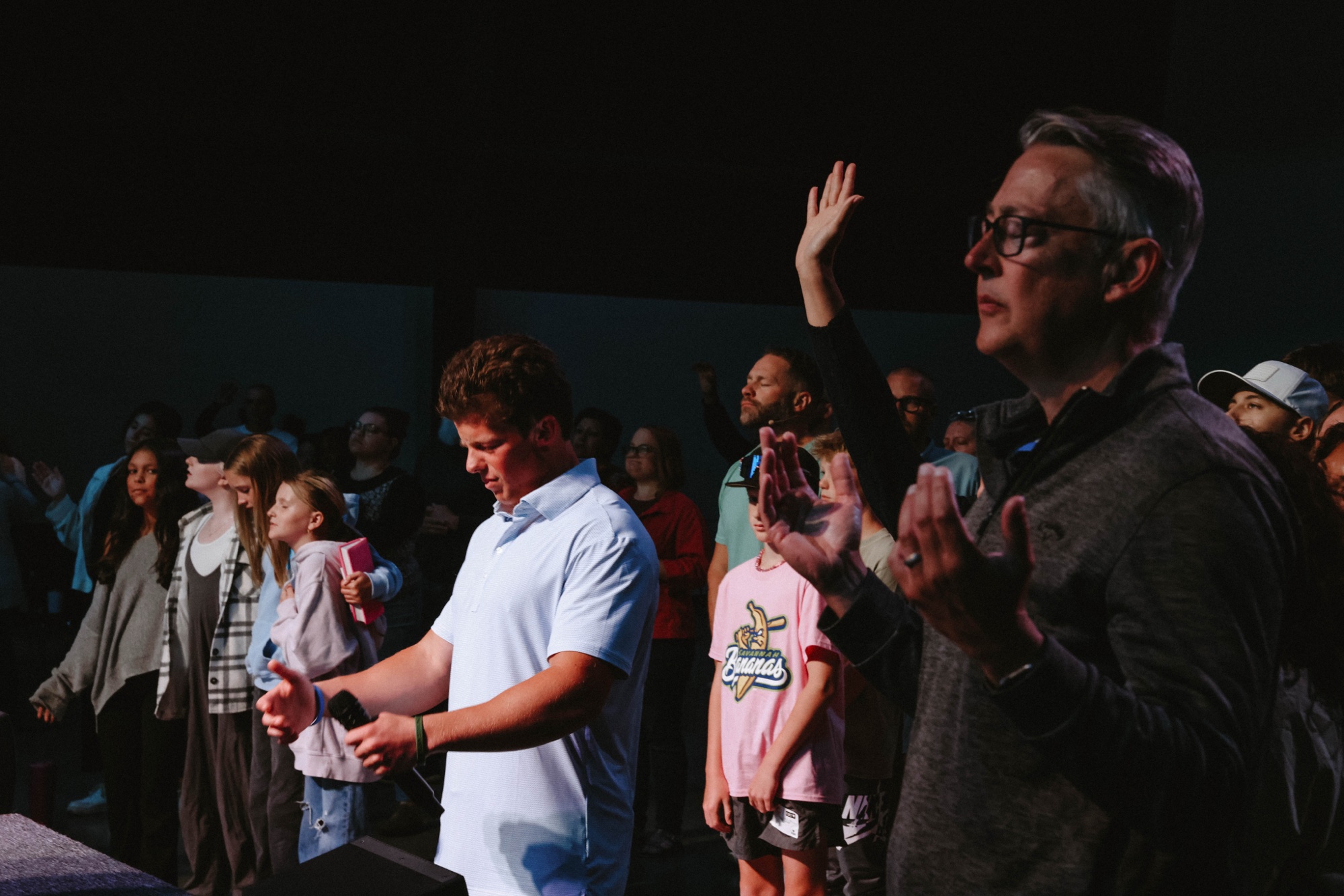 Dylan worshiping with a congregation, hands raised
